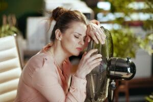 Woman Worker In Modern Green Office With Electric Fan Suffering From the Arizona Summer Heat